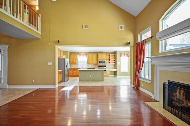 9406 Laurel Wind Ct, Houston, TX 77040 - unfurnished living room with high vaulted ceiling, a premium fireplace, light wood-type flooring, and plenty of natural light