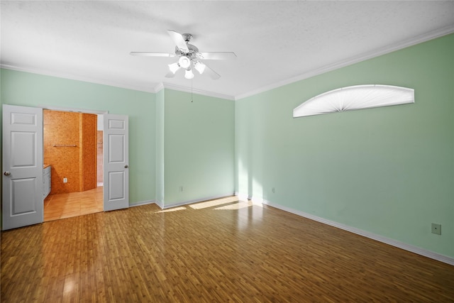 empty room featuring crown molding, wood finished floors, baseboards, and ceiling fan