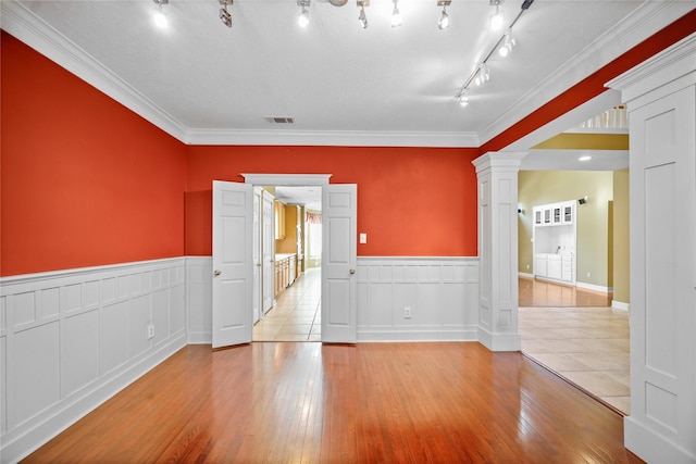 empty room with visible vents, hardwood / wood-style floors, wainscoting, and ornate columns