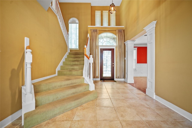 foyer entrance with tile patterned flooring, a high ceiling, plenty of natural light, and ornate columns