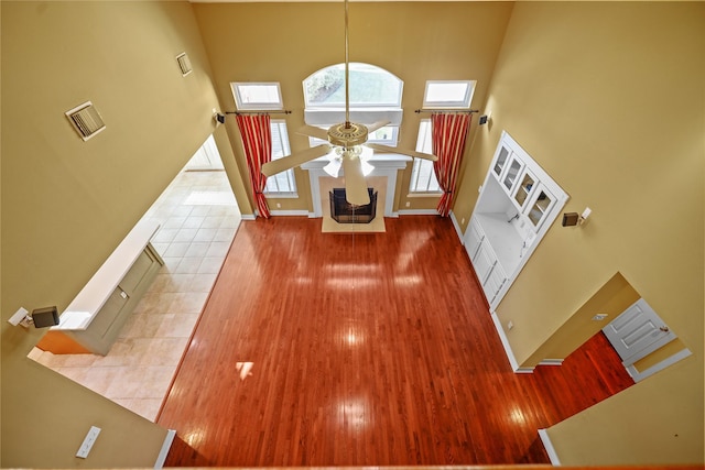 entrance foyer with wood finished floors, visible vents, baseboards, ceiling fan, and a towering ceiling