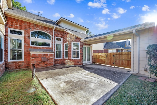 rear view of property featuring a patio, fence, brick siding, and a shingled roof