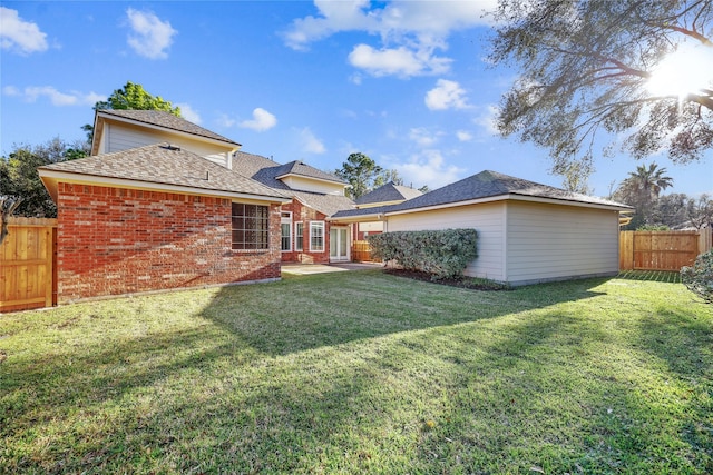 back of property featuring a patio, fence, a lawn, and brick siding