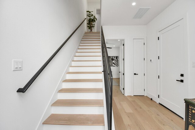 staircase with wood finished floors, visible vents, and recessed lighting