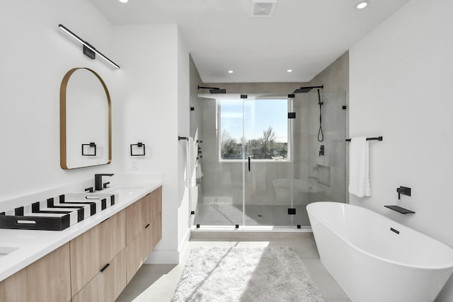 full bathroom featuring a stall shower, a freestanding tub, visible vents, and double vanity