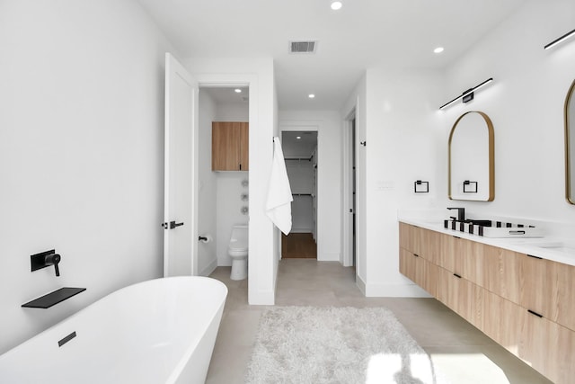 bathroom with visible vents, toilet, a soaking tub, finished concrete floors, and vanity