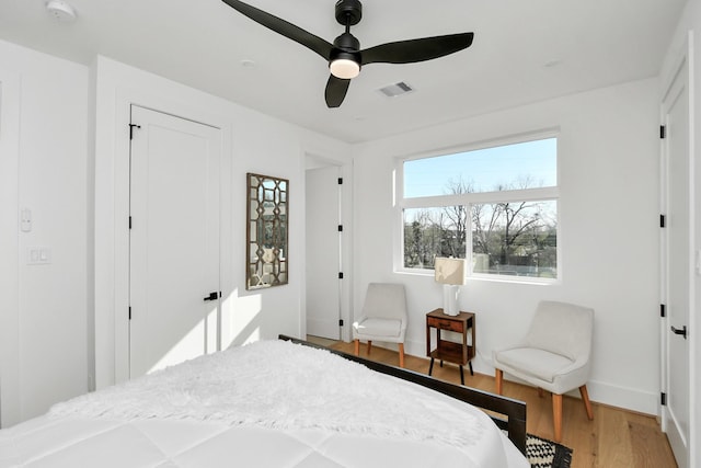 bedroom featuring visible vents, ceiling fan, baseboards, and wood finished floors