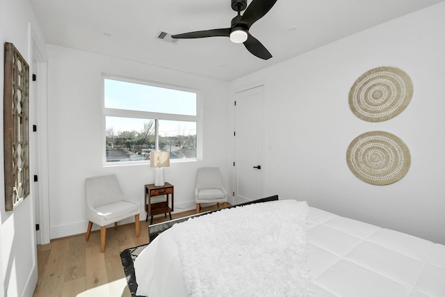 bedroom with baseboards, light wood-type flooring, visible vents, and a ceiling fan