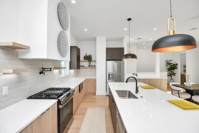 kitchen with a sink, light countertops, appliances with stainless steel finishes, open shelves, and modern cabinets