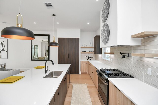 kitchen with modern cabinets, stainless steel appliances, light countertops, open shelves, and a sink