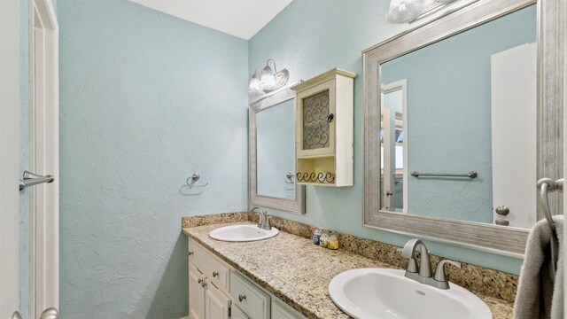 full bath featuring double vanity, a sink, and a textured wall