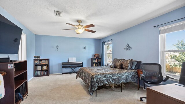 carpeted bedroom featuring baseboards, visible vents, a ceiling fan, and a textured ceiling