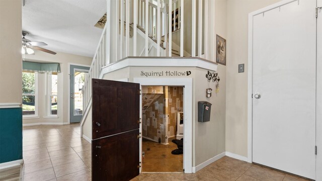 tiled entrance foyer with a ceiling fan and baseboards