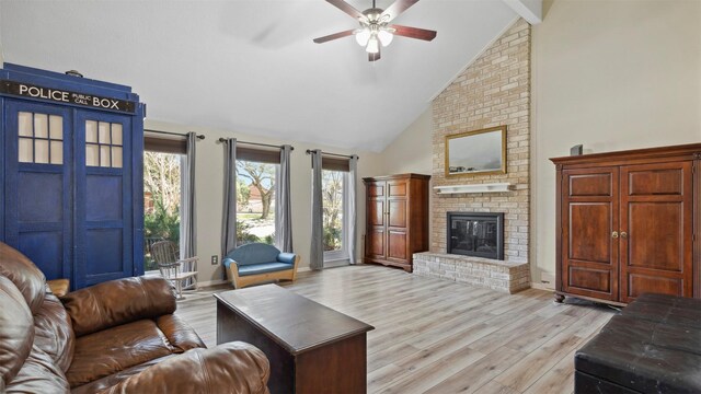 living room featuring baseboards, ceiling fan, light wood-type flooring, a brick fireplace, and high vaulted ceiling