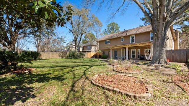 rear view of property with a fenced backyard, a lawn, and a patio