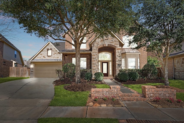 french country home with a garage, stone siding, brick siding, and driveway