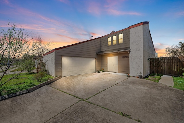 view of front of property featuring concrete driveway, an attached garage, and fence