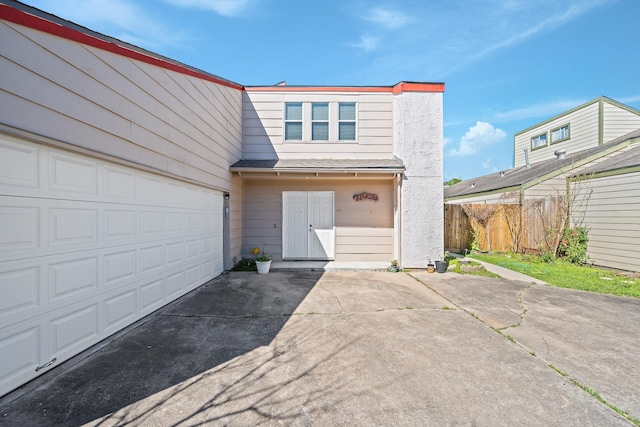 view of front facade with a garage, roof with shingles, driveway, and fence