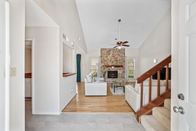 living room with visible vents, ceiling fan, stairs, a fireplace, and high vaulted ceiling