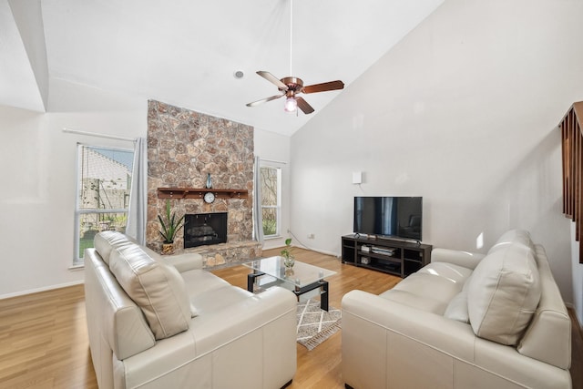 living room featuring a healthy amount of sunlight, light wood finished floors, a fireplace, and high vaulted ceiling