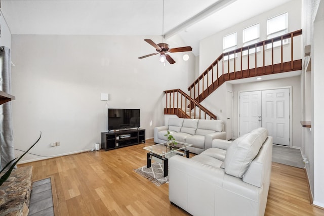 living room with light wood-style floors, baseboards, high vaulted ceiling, and beam ceiling