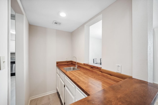 kitchen with a sink, visible vents, and white cabinetry