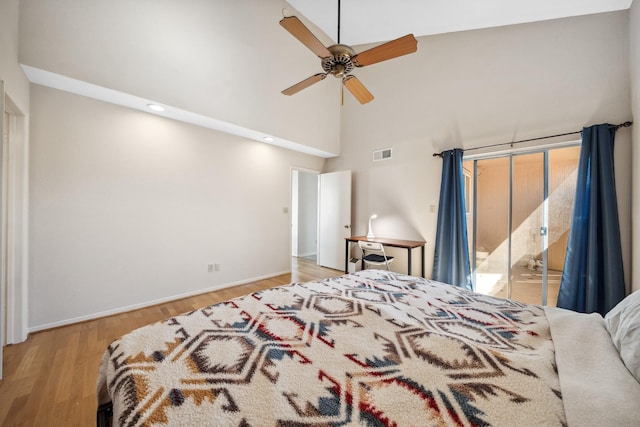 bedroom featuring visible vents, a ceiling fan, a towering ceiling, wood finished floors, and access to exterior