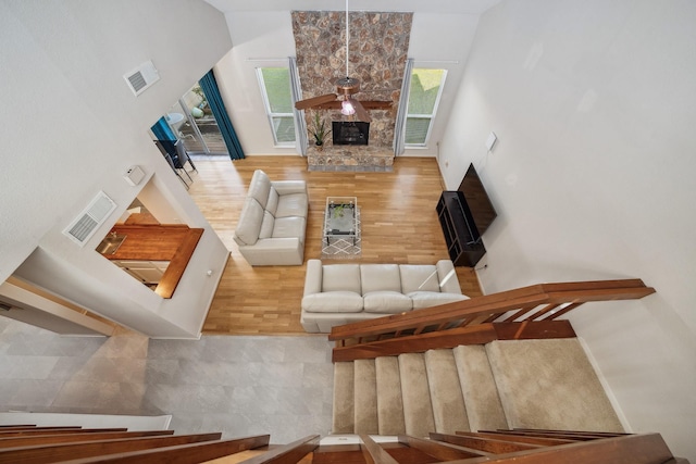 living room featuring a stone fireplace, wood finished floors, and visible vents