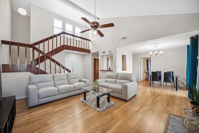 living room with ceiling fan with notable chandelier, visible vents, baseboards, stairs, and light wood-type flooring