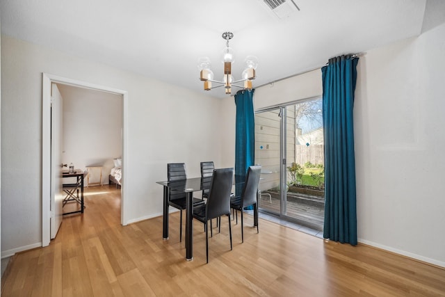 dining room featuring light wood finished floors, visible vents, a chandelier, and baseboards