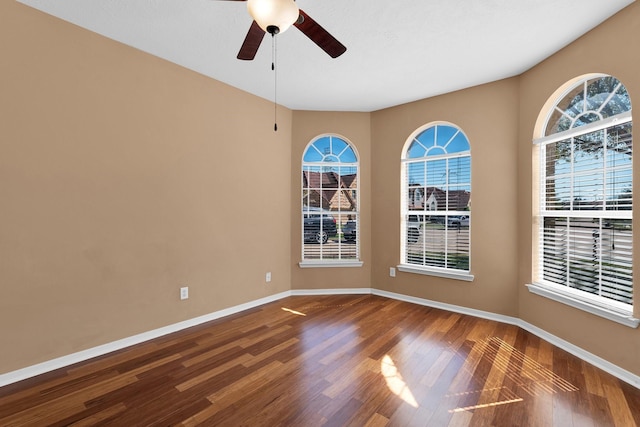 spare room with ceiling fan, wood finished floors, and baseboards