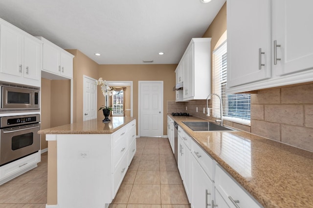 kitchen with light tile patterned floors, stainless steel appliances, a sink, and a healthy amount of sunlight