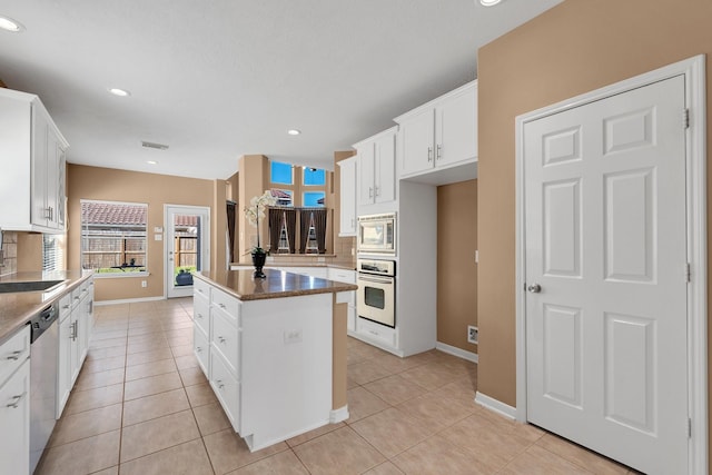 kitchen with light tile patterned floors, stainless steel appliances, a center island, and decorative backsplash