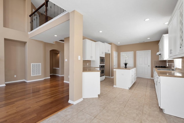 kitchen featuring a center island, stainless steel appliances, visible vents, white cabinets, and baseboards
