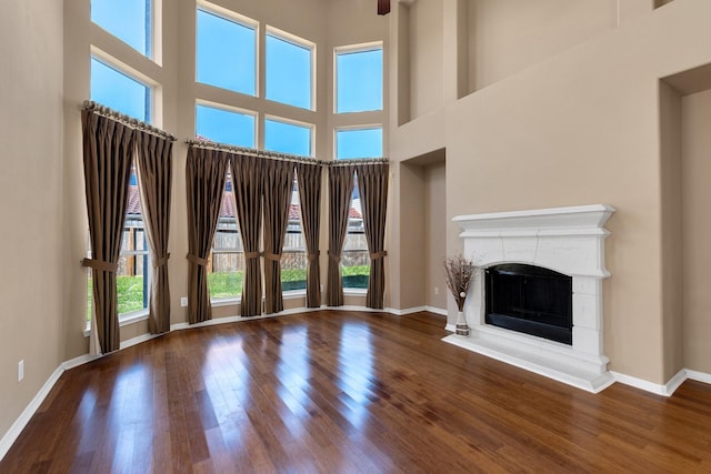 unfurnished living room featuring a fireplace with raised hearth, wood finished floors, and baseboards