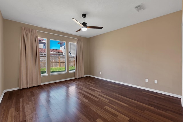 empty room with dark wood-type flooring, visible vents, ceiling fan, and baseboards