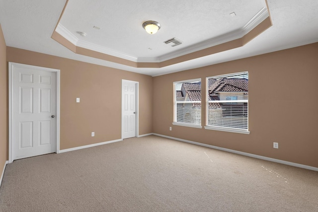 unfurnished room with a tray ceiling, visible vents, and crown molding