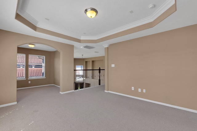 spare room featuring ornamental molding, a tray ceiling, and baseboards