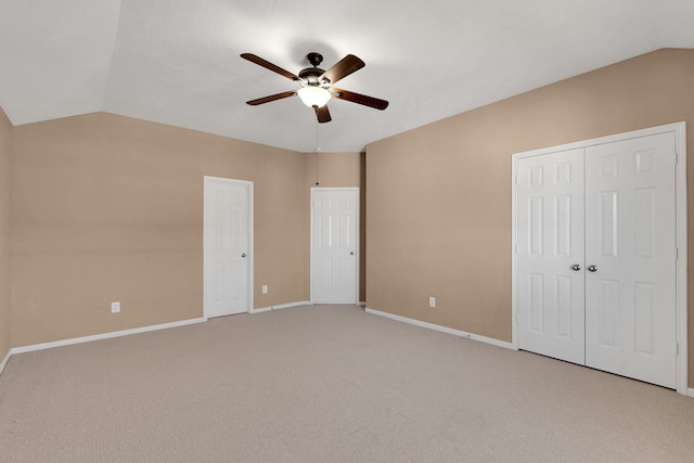 unfurnished bedroom with lofted ceiling, a closet, light carpet, ceiling fan, and baseboards