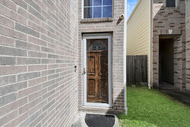 entrance to property with fence and brick siding