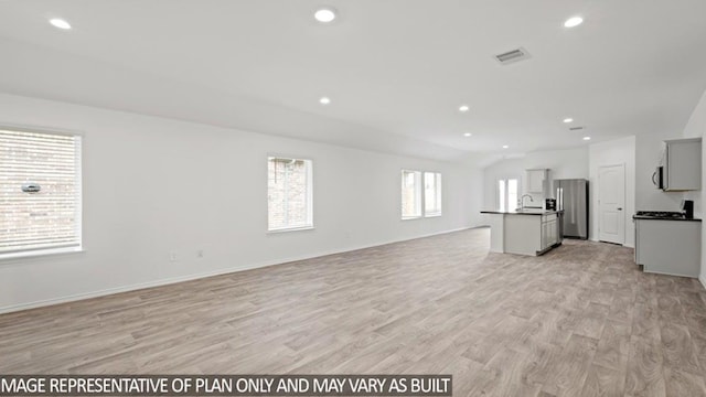 unfurnished living room with light wood-style flooring, a sink, visible vents, and recessed lighting