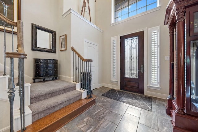 foyer featuring stairs, a high ceiling, and baseboards