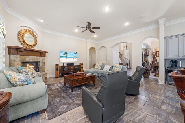 living area featuring arched walkways, beverage cooler, a fireplace, and crown molding