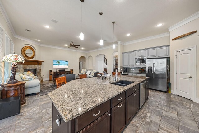 kitchen featuring ornamental molding, a sink, open floor plan, stainless steel appliances, and arched walkways