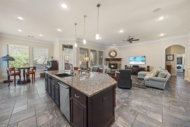 kitchen with crown molding, baseboards, a fireplace, arched walkways, and a sink