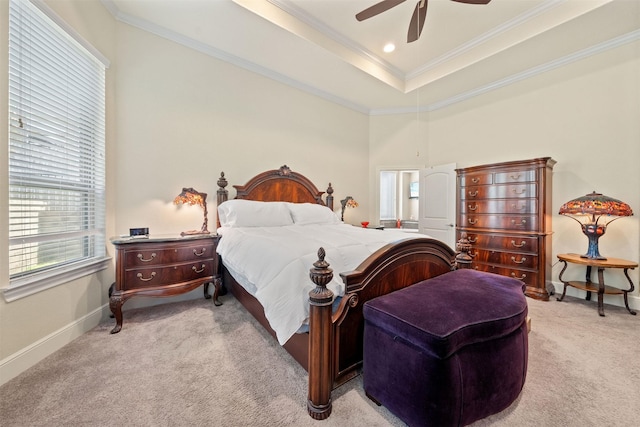 bedroom with a ceiling fan, baseboards, a tray ceiling, crown molding, and light colored carpet