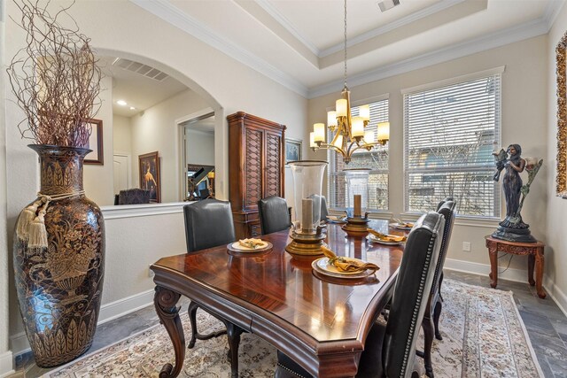 dining room featuring arched walkways, visible vents, a raised ceiling, and a wealth of natural light