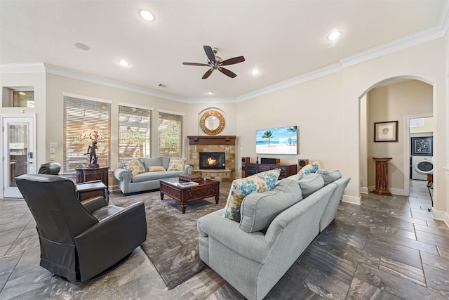 living area with arched walkways, washer / clothes dryer, baseboards, and ornamental molding