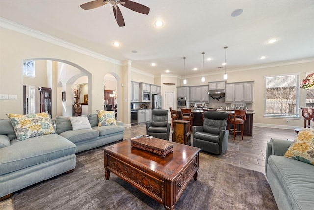 living room featuring crown molding, recessed lighting, baseboards, and arched walkways