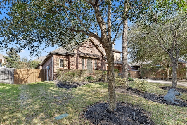 view of front of property featuring brick siding, a front lawn, and fence